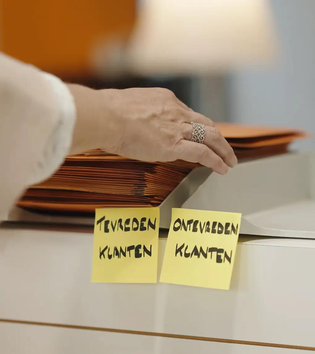 Folders in bakje met tevreden klanten